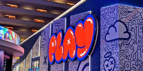 Illuminated red PLAY sign on a doodle-patterned wall at Play Playground
