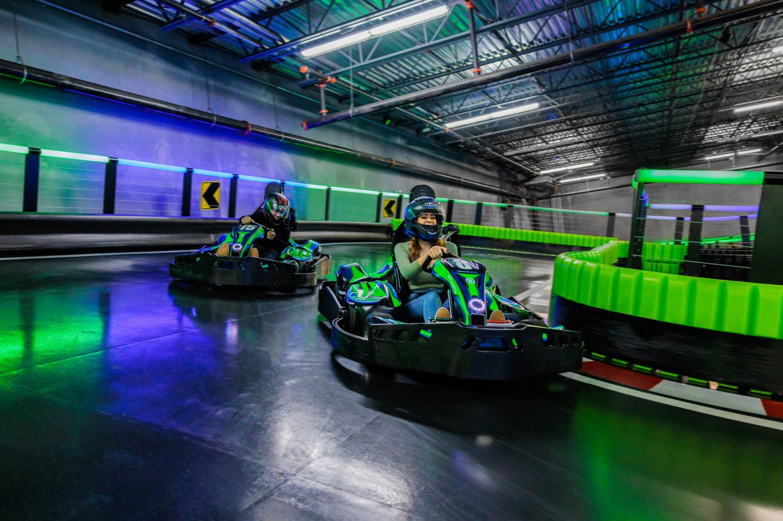 Two drivers racing electric go-karts on the indoor track at Andretti Chandler