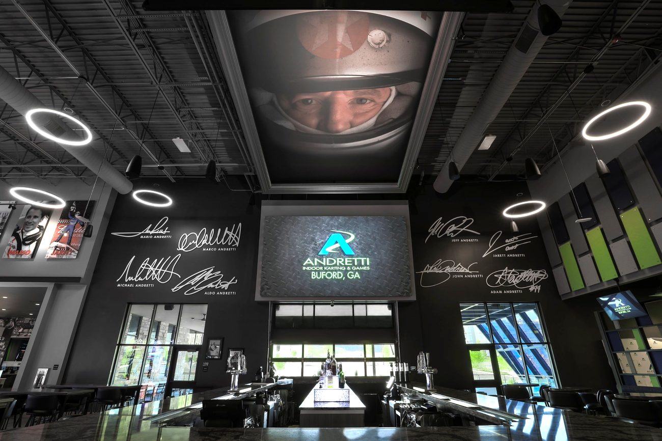 Inside Andretti Indoor Karting & Games with a large video screen above the bar