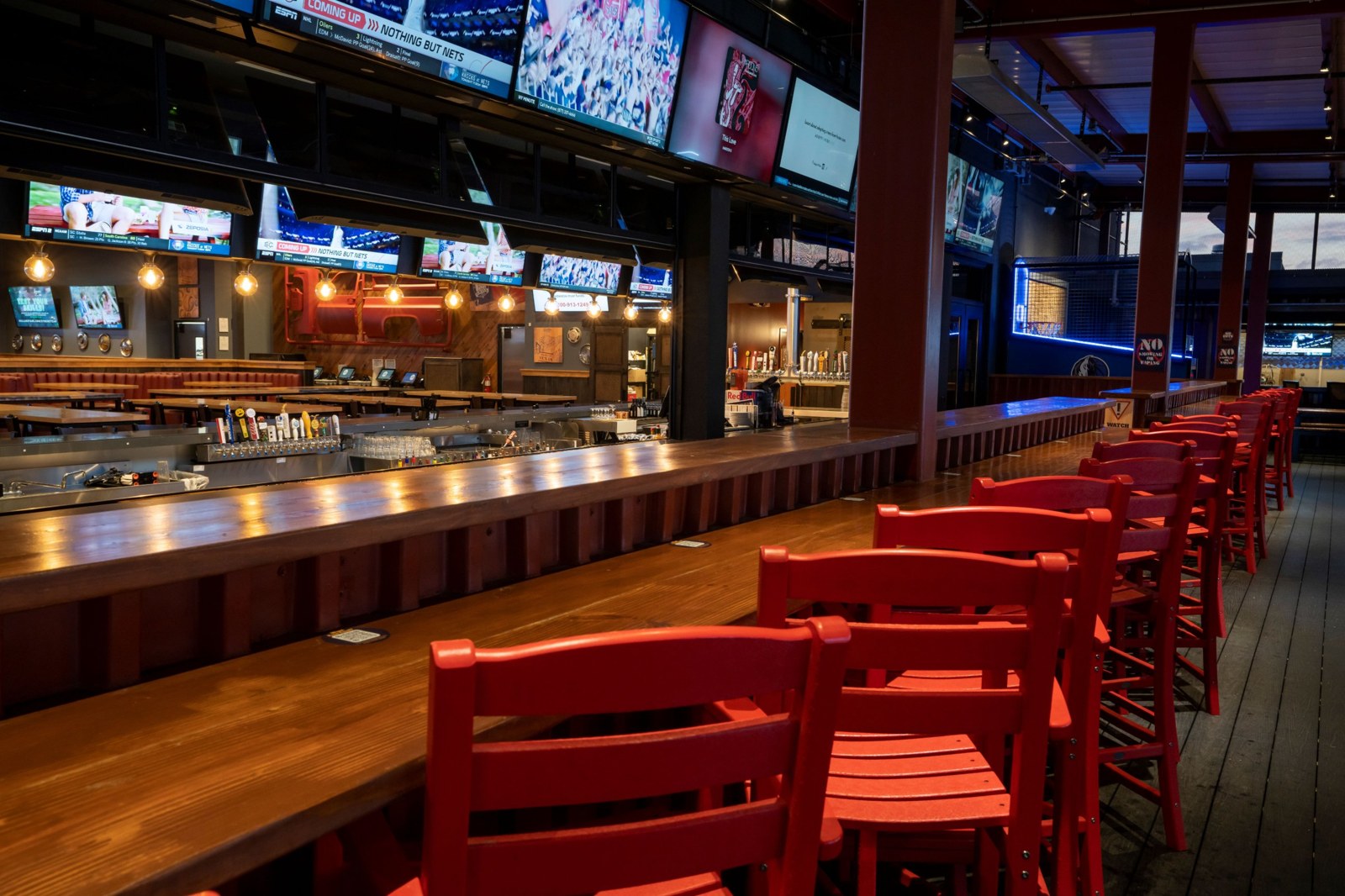 Main bar with overhead TVs, wood bar top and red stools at BoomerJack's Grill