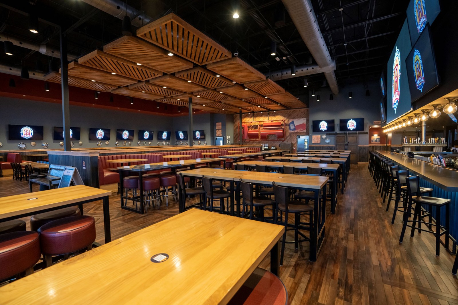 Dining room with wood ceiling canopy, booths and TVs showing the BoomerJack's logo