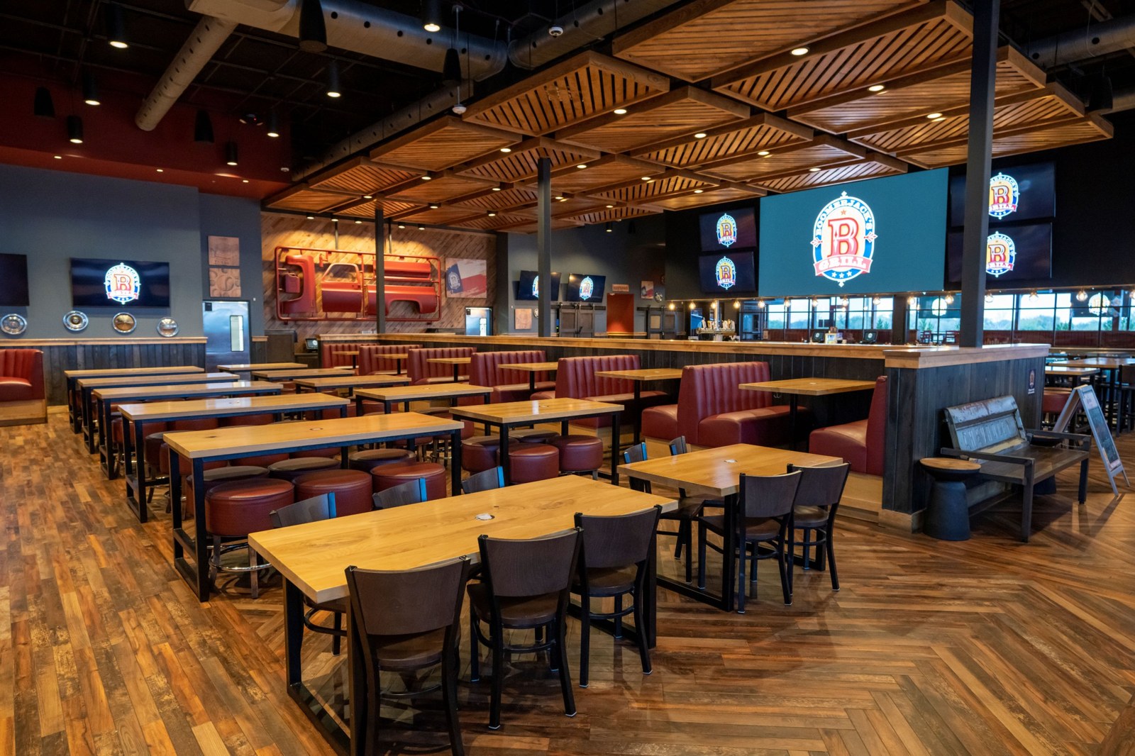 Dining area with high-top tables, red booths and a large LED video wall