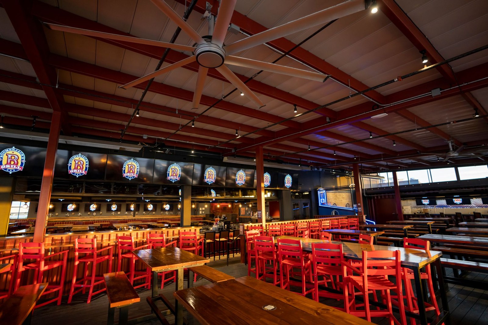 Covered patio with red stools, picnic tables, ceiling fans and a row of TVs