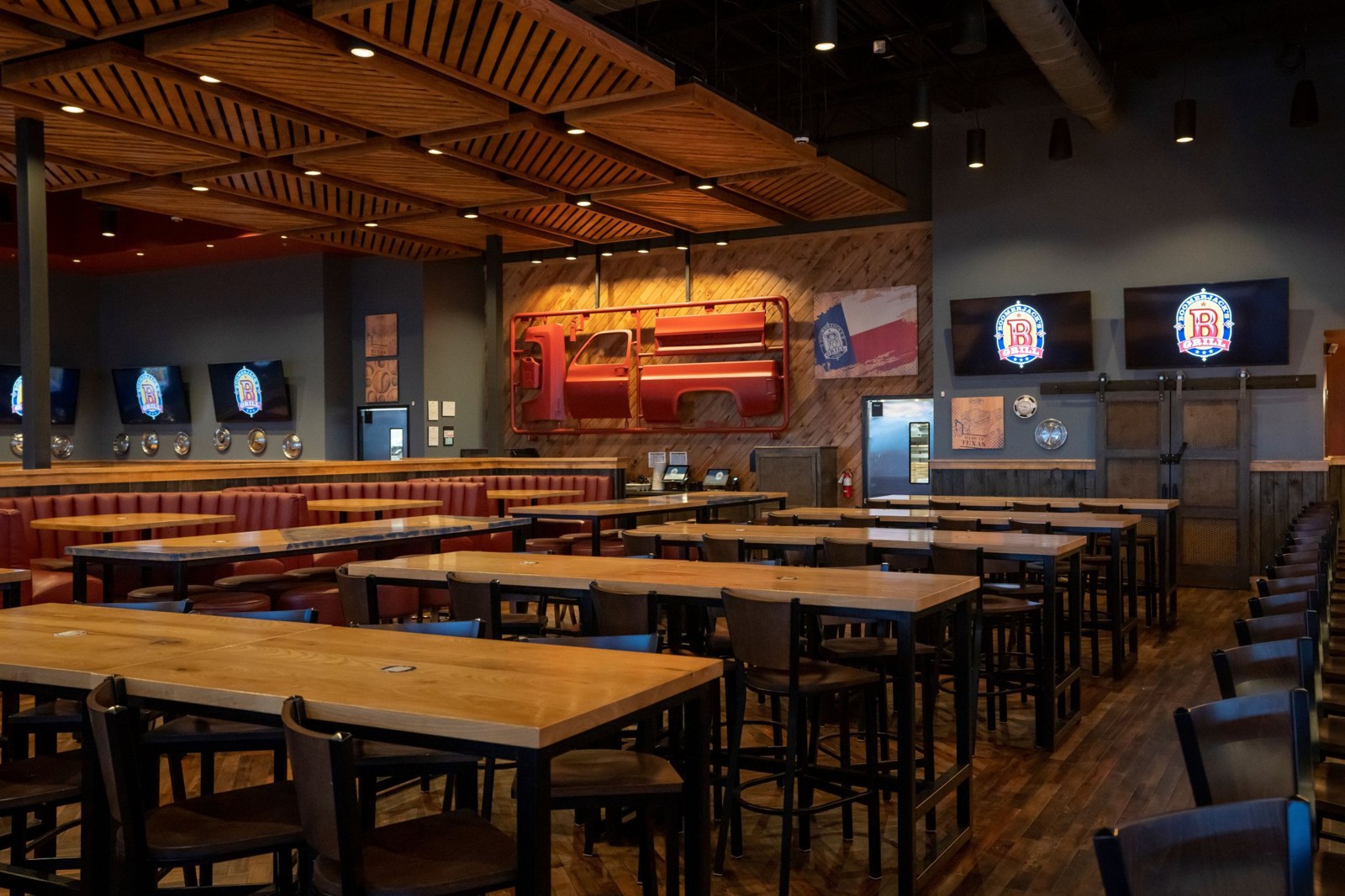 Dining room feature wall with red truck-body art, Texas flag and TVs