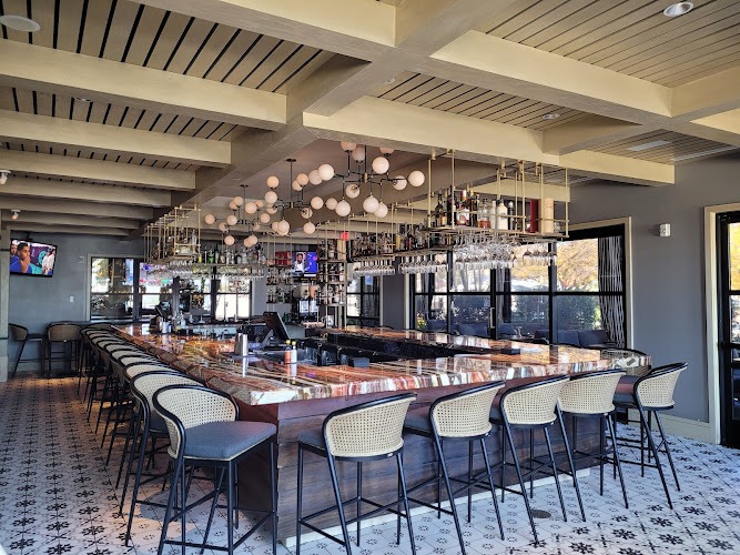 Calabrese bar with marble counter, rattan stools, globe lights and hanging glass racks