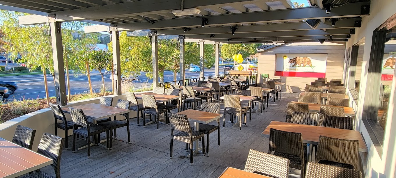 California Pizza Kitchen covered patio with tables, chairs and a California bear mural