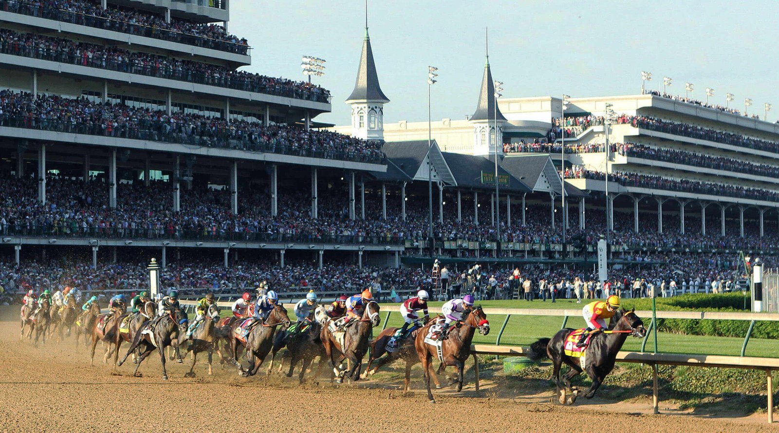Horses racing past the packed grandstands and twin spires at Churchill Downs