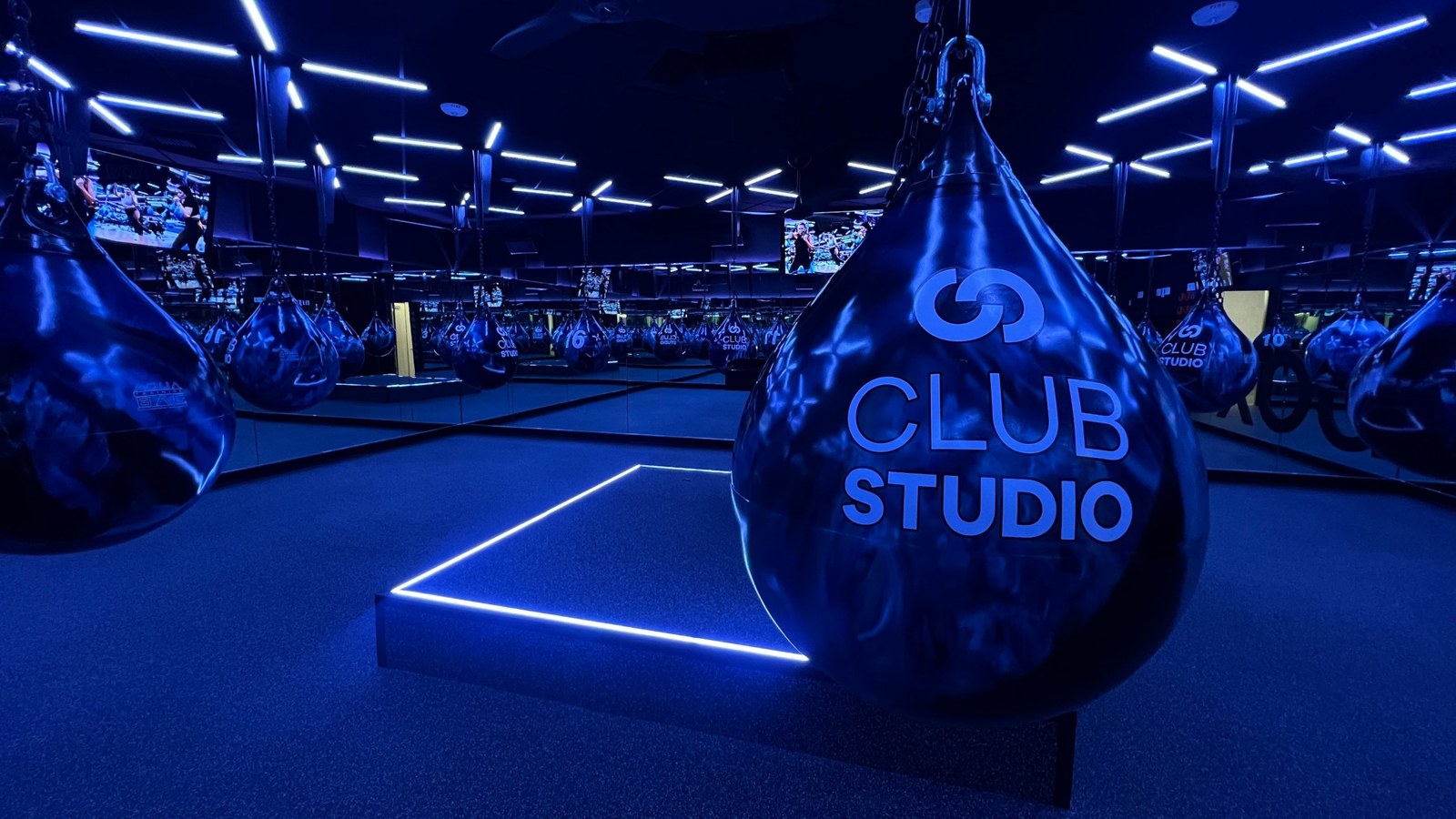 Club Studio boxing area with hanging water bags, blue LED lines and screens