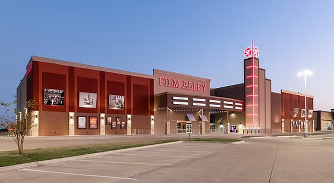 Film Alley theater exterior in Terrell, Texas at dusk with red lighting on the tower