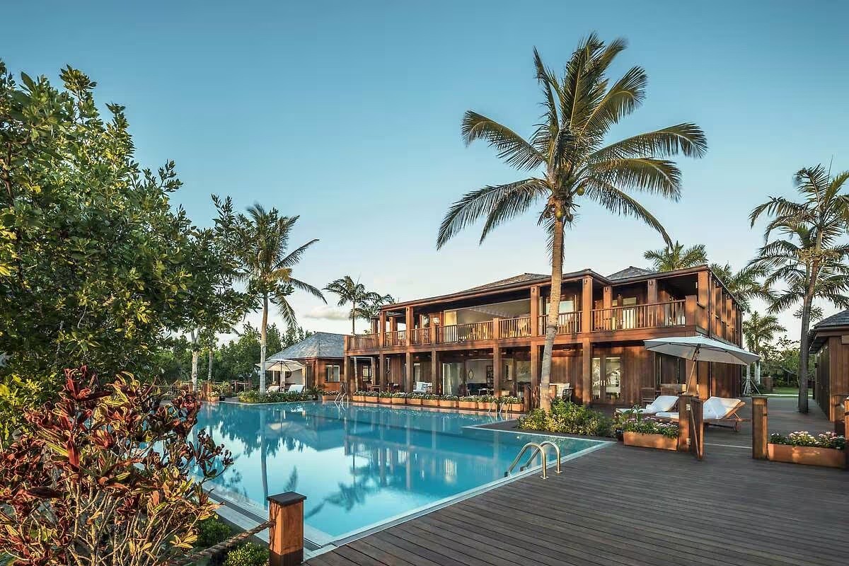 Hotel Como Parrot Cay pool, wood deck and two-story villa framed by palm trees