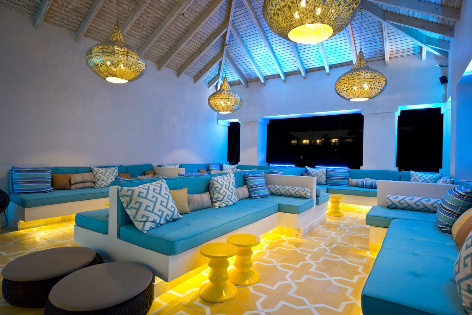 Hyatt Ziva Rose Hall lounge with turquoise seating, brass pendant lights and glowing yellow accents