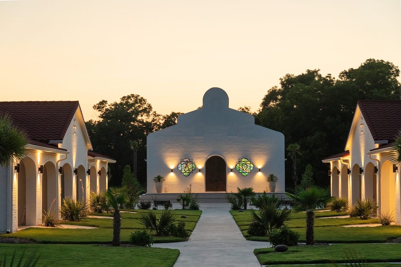 Chapel front at dusk with lit stained glass and warm wall lighting