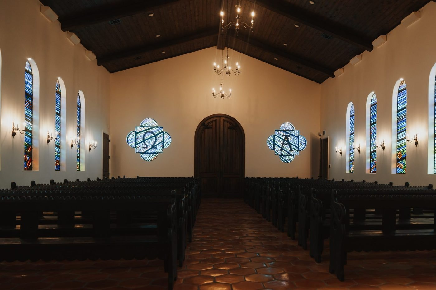 Casa Del Rey Chapel interior with dark wood ceiling, stained glass windows and pews