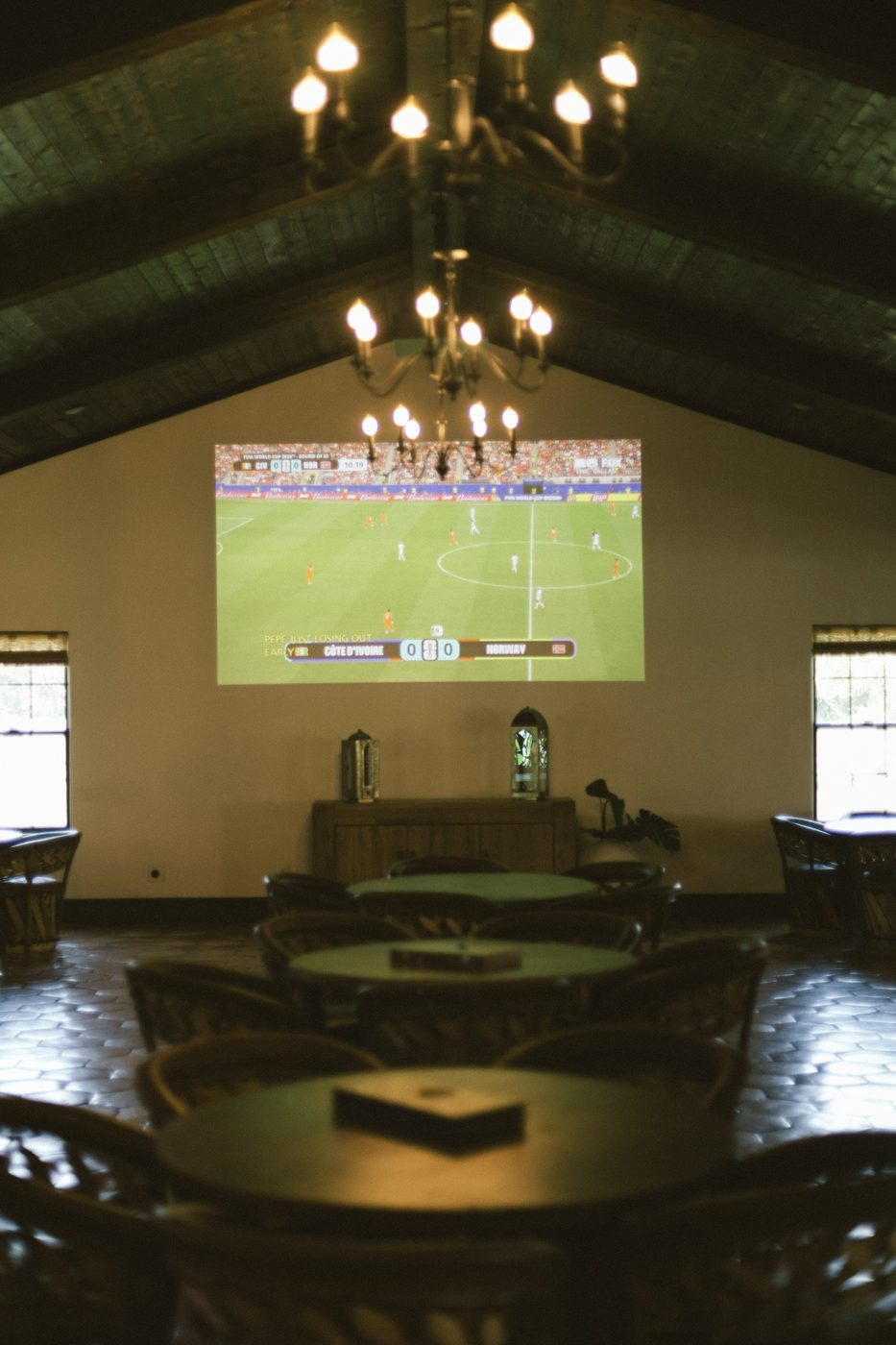 Projector screen showing a live match in the reception hall under chandeliers