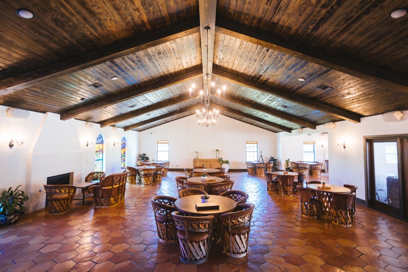 Reception hall with wood beam ceiling, chandeliers and round tables