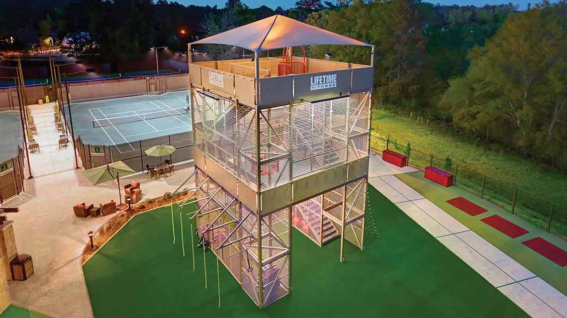 Aerial view of a Lifetime Fitness outdoor activity tower beside tennis courts at night