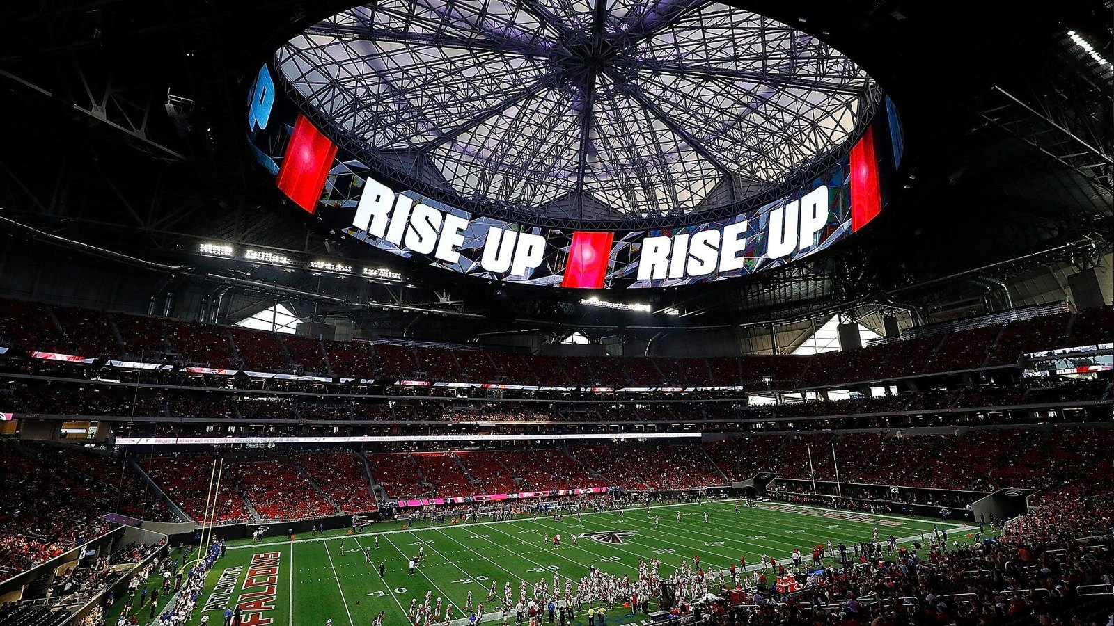 Inside Mercedes-Benz Stadium in Atlanta with the halo video board and open roof above the field