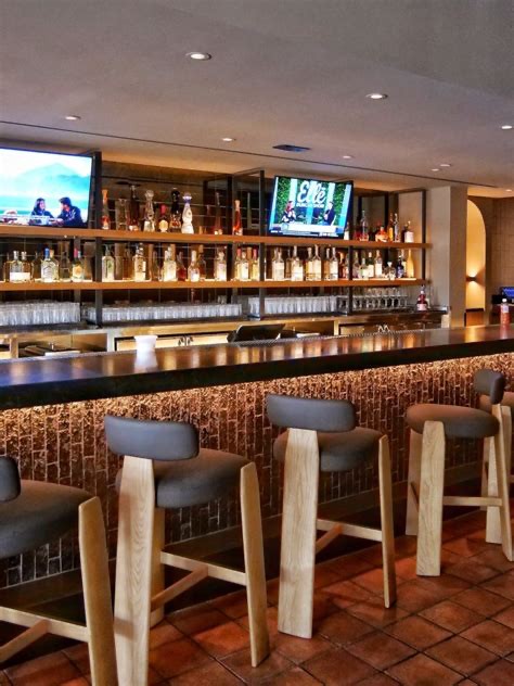 Mi Cocina bar with backlit shelves of spirits, TVs and wood bar stools
