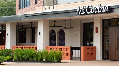 Mi Cocina storefront in Houston with arched stained-glass windows and orange planter walls