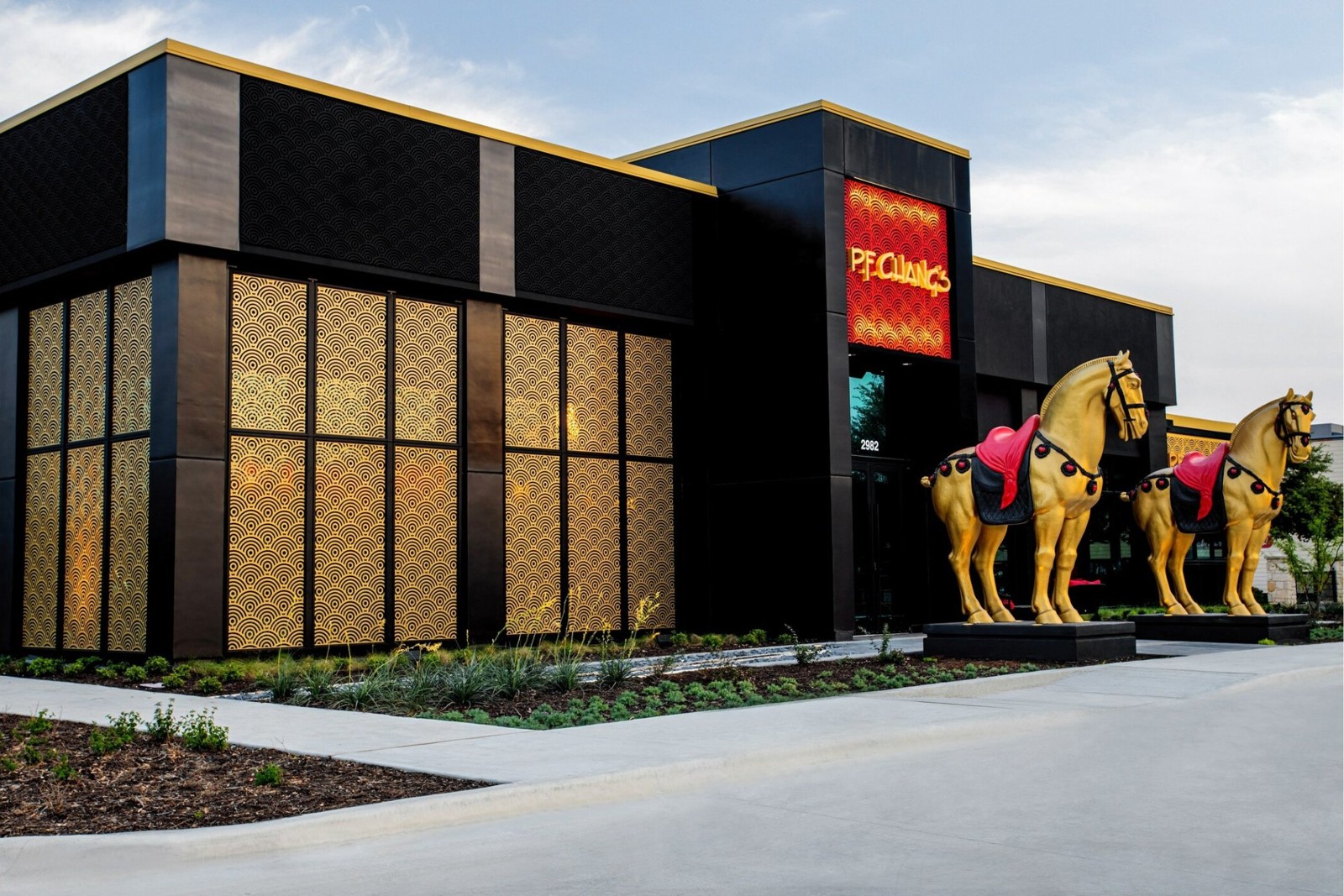 P.F. Chang's New Braunfels exterior with gold patterned panels, red sign and two gold horse statues