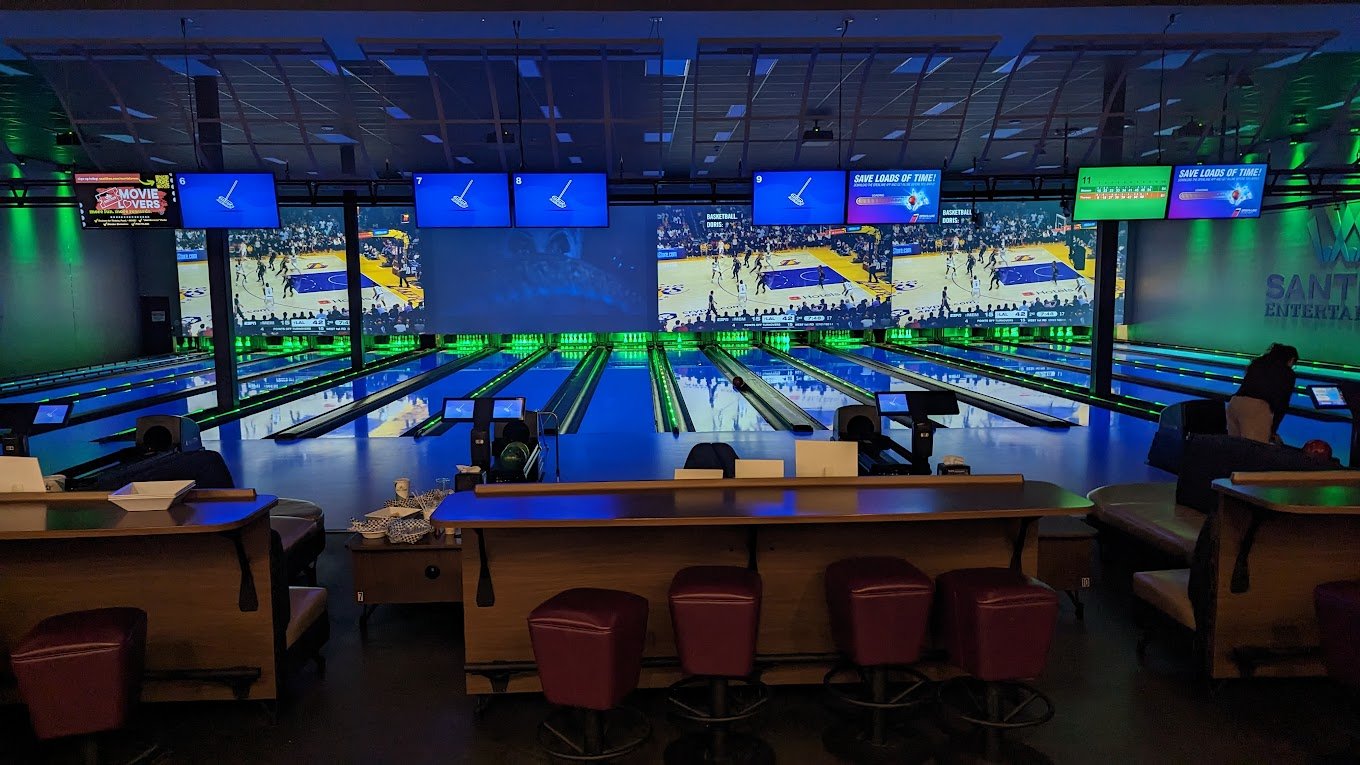 Bowling lanes at Santikos Cibolo with a video wall showing a basketball game and TVs above each lane