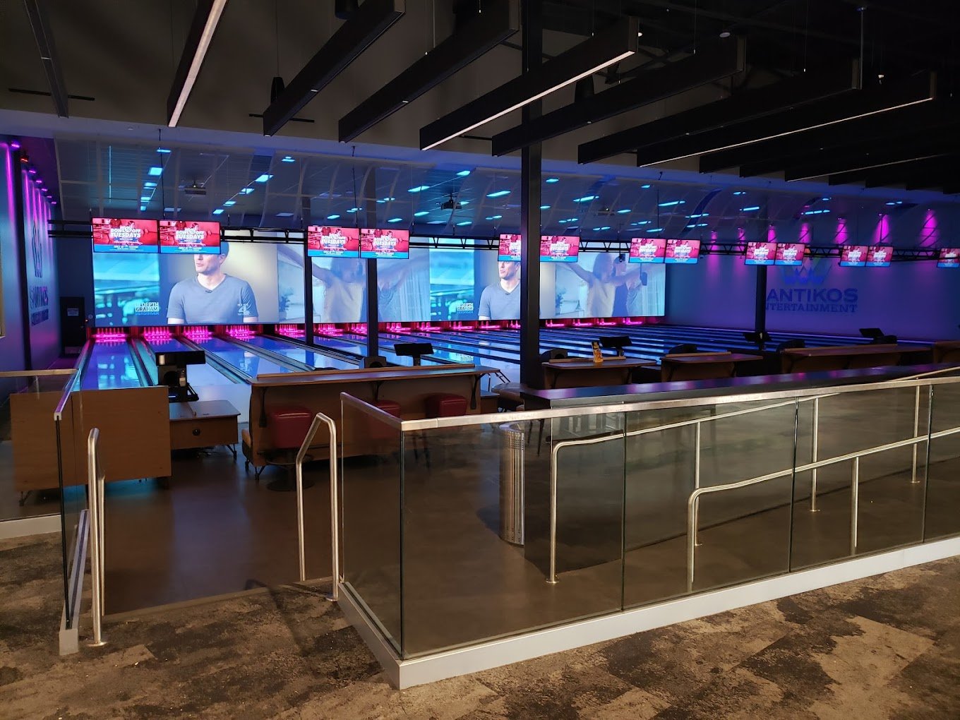 Bowling lanes at Santikos Cibolo with a large video wall and pink accent lighting