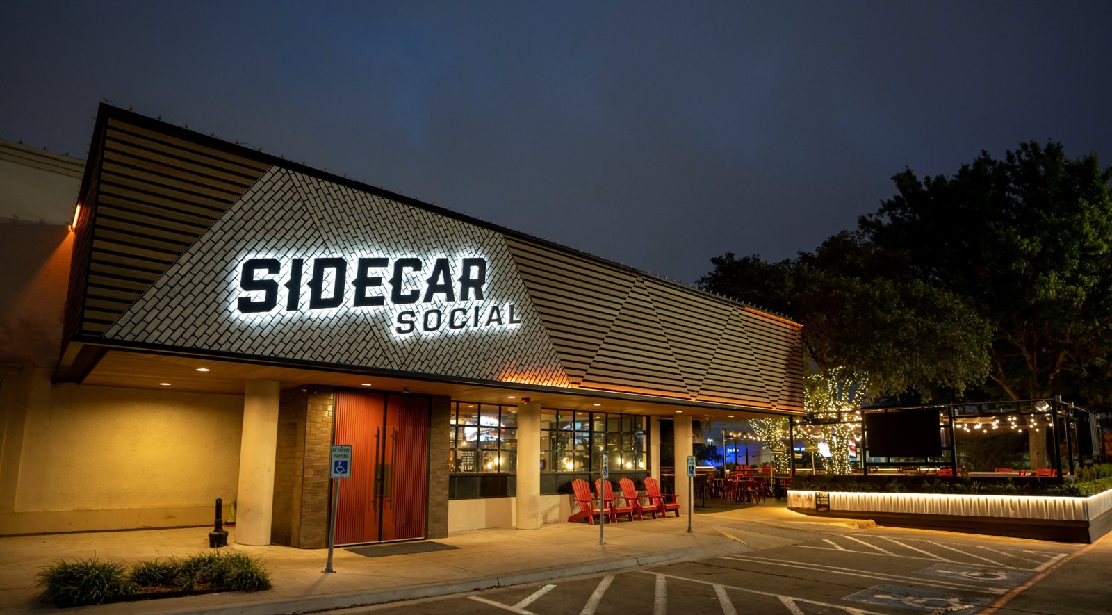 Sidecar Social in Addison, Texas at night with illuminated sign and patio lighting