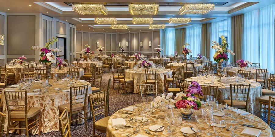 The Whitley ballroom set for a banquet with round tables, gold chairs and floral centerpieces