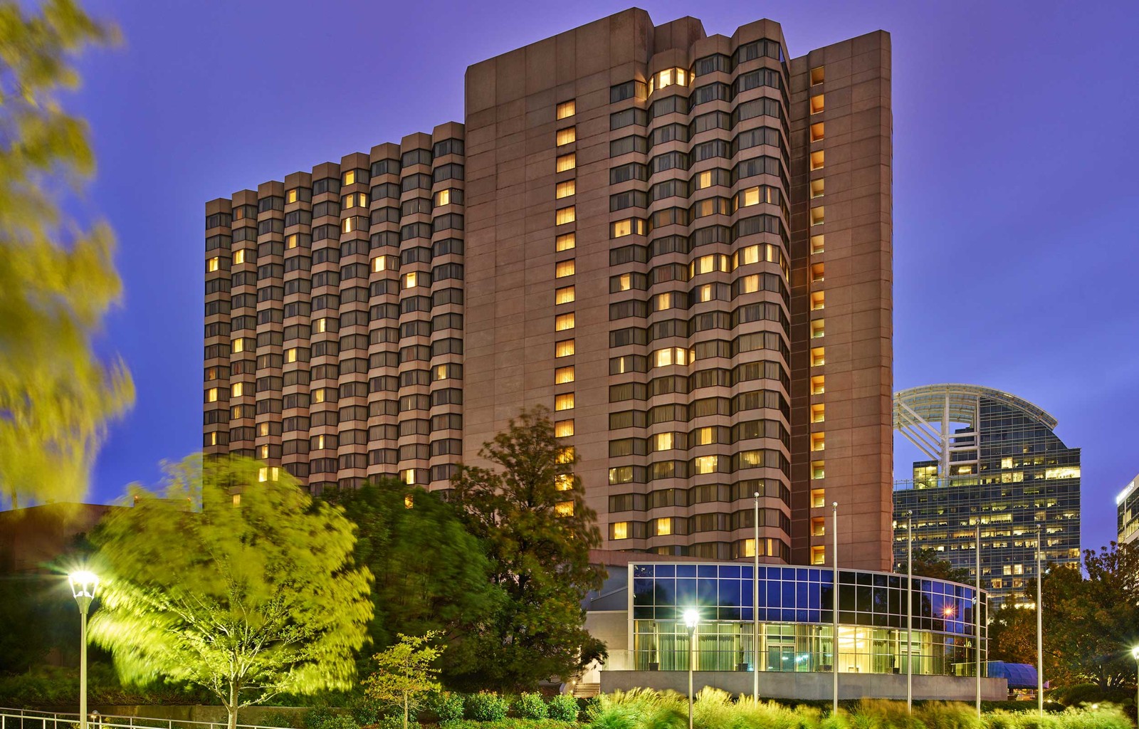 The Whitley hotel tower in Atlanta at dusk with lit windows and landscaped grounds