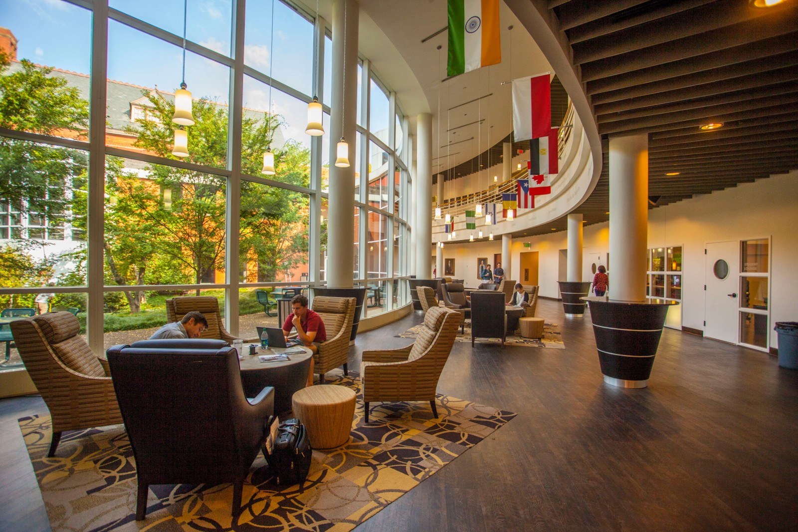 Owen School atrium lounge with floor-to-ceiling windows, pendant lights and international flags