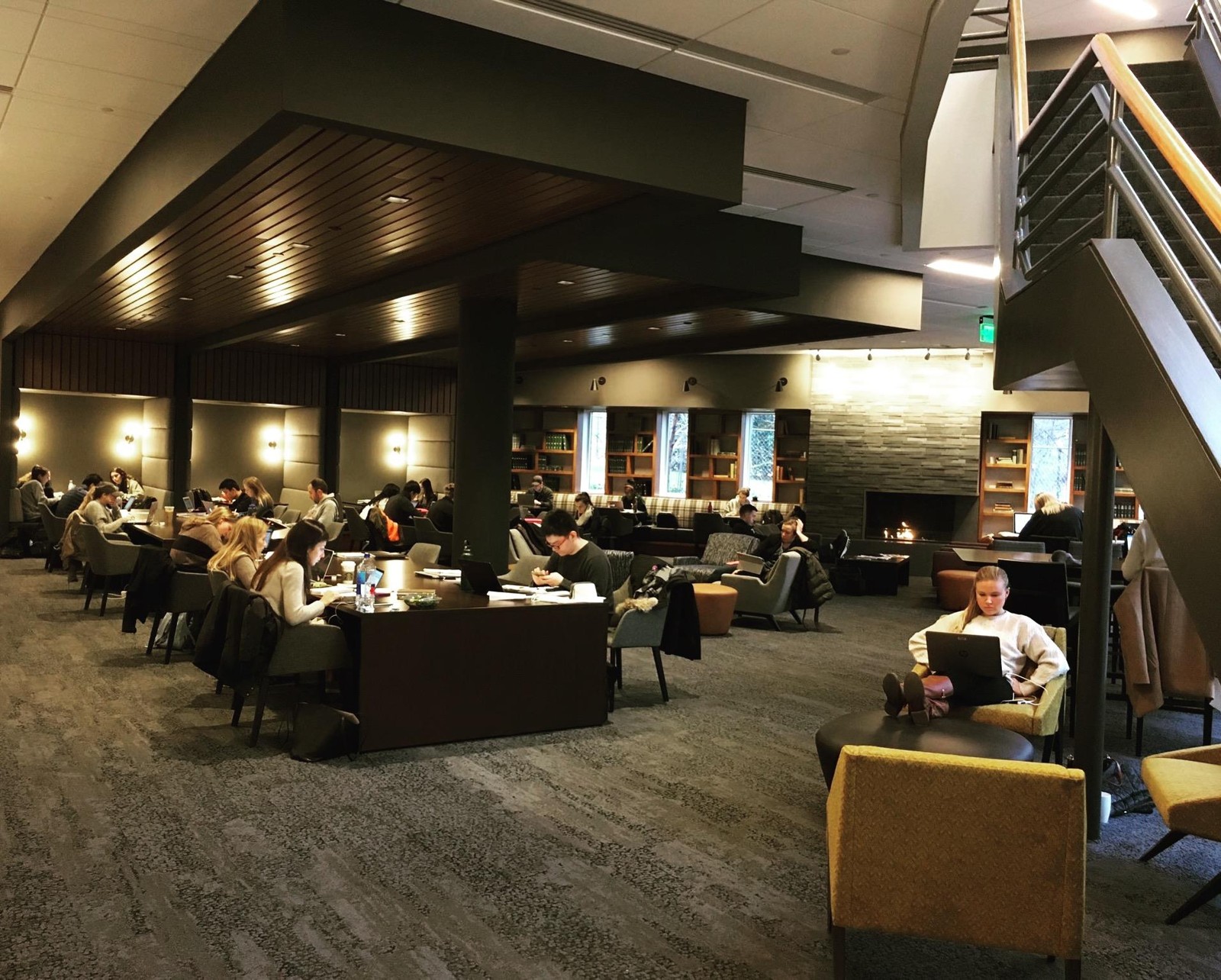Owen School study lounge with long tables, wall sconces, fireplace and bookshelves